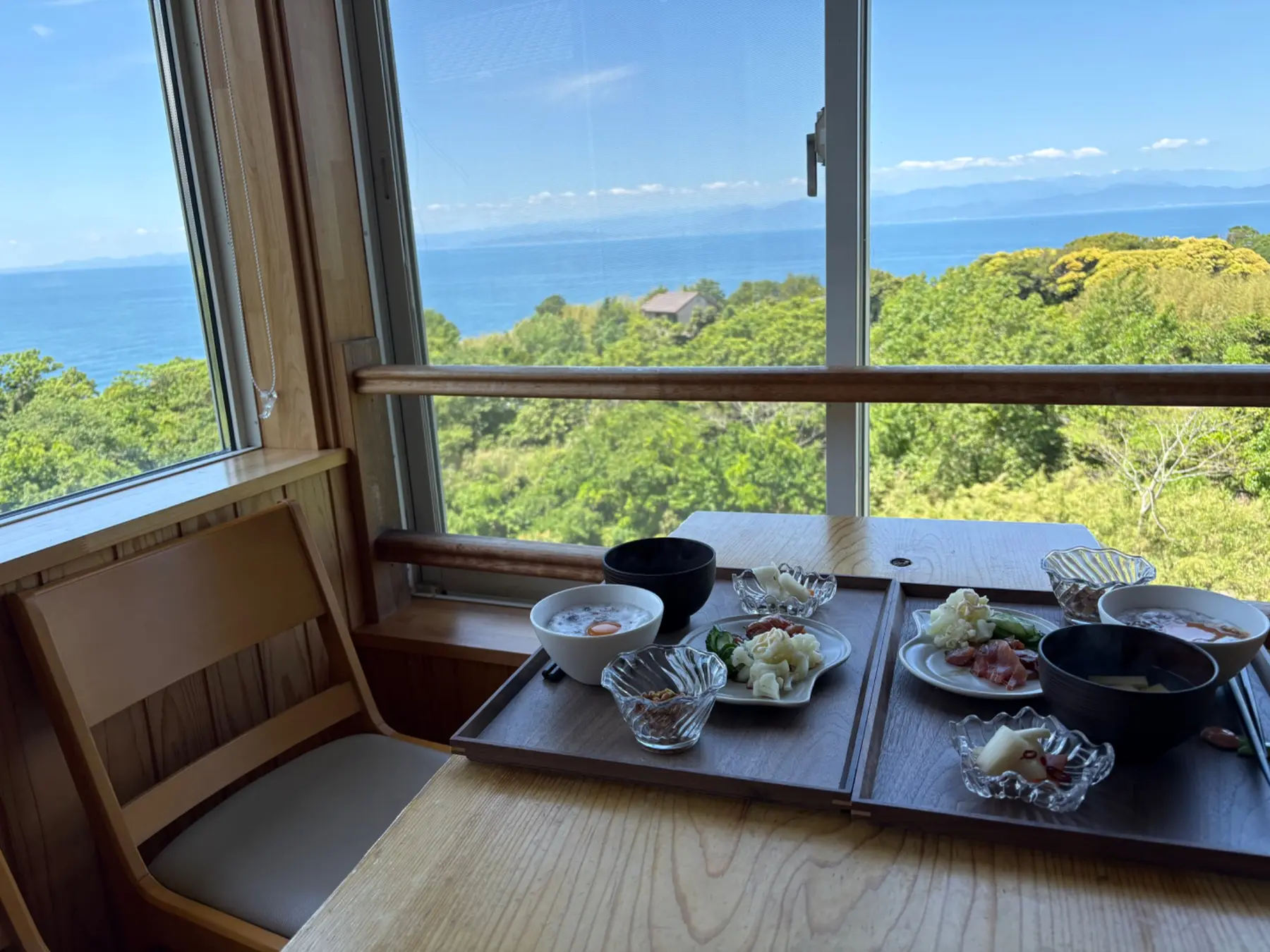 店内の窓辺の席から料理とともに望む青い海