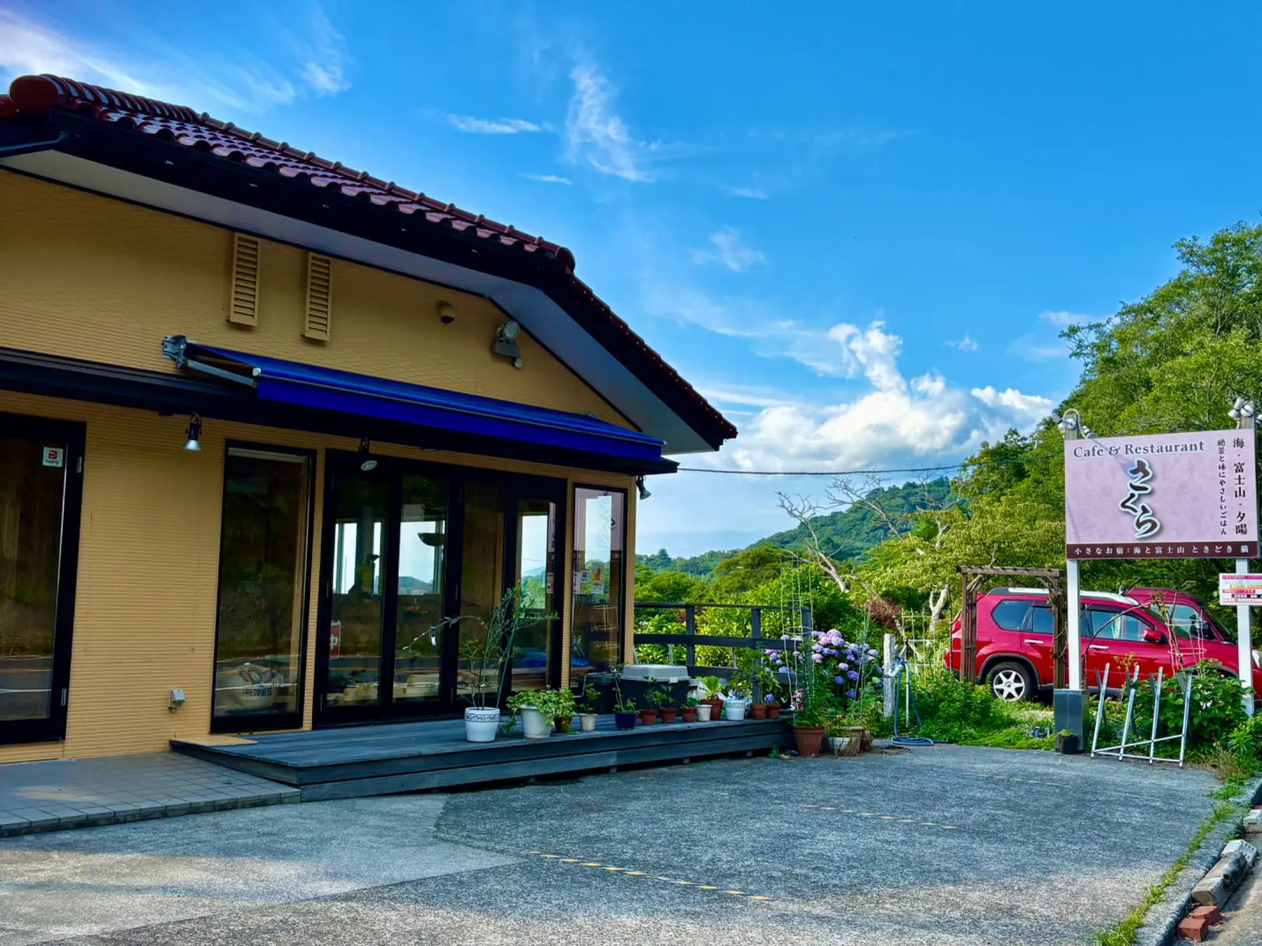 カフェ&レストランさくらの店舗前にある舗装駐車場と看板奥の砂利駐車場
